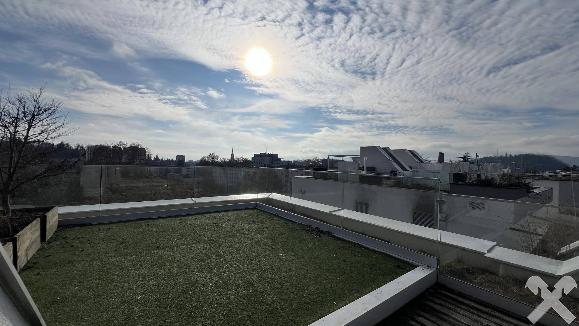 Sonnige Dachterrasse mit weitem Ausblick, Glasgeländer und Grünflächen für Entspannung im Freien.