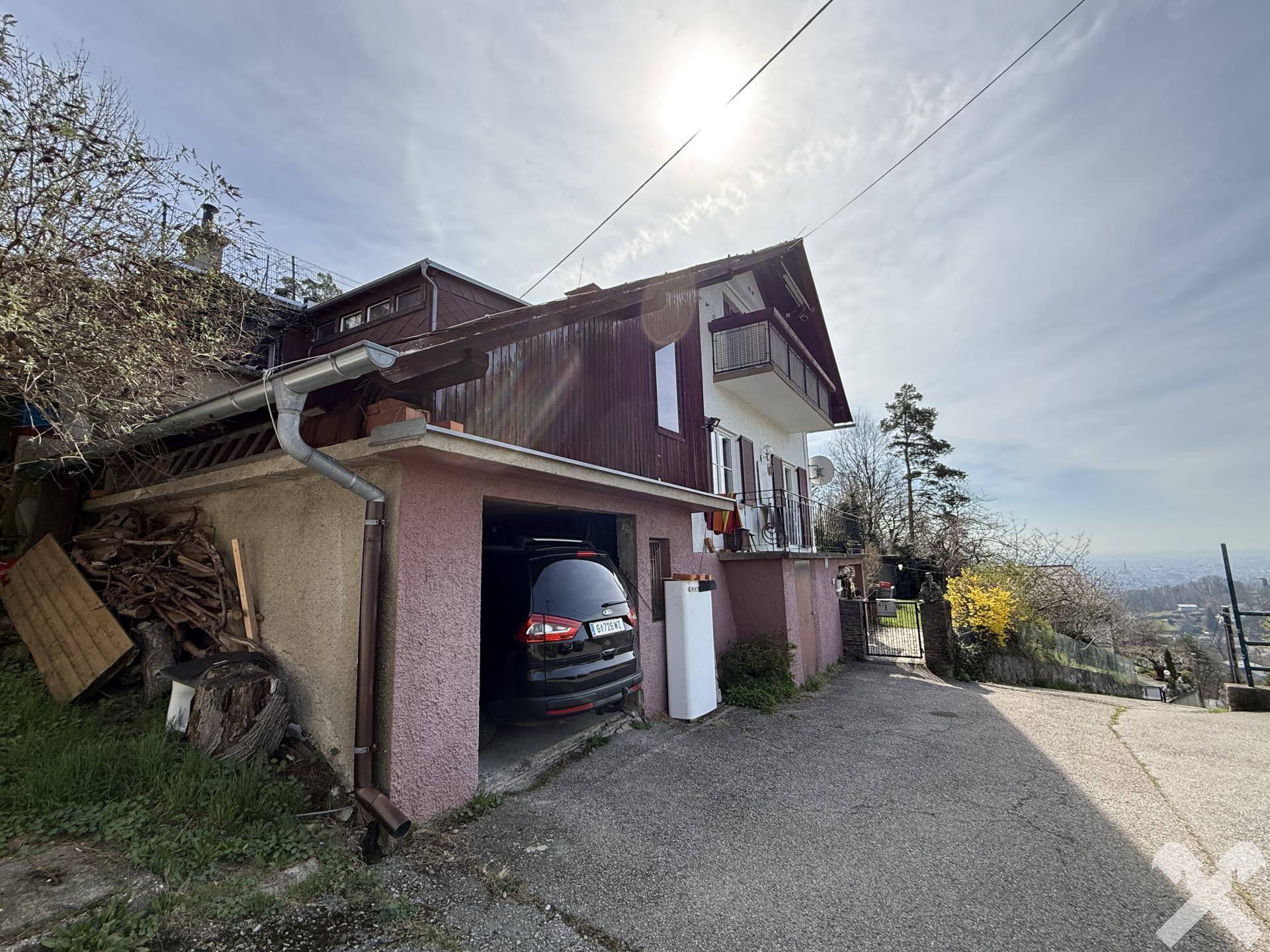 Außenansicht des Hauses mit integrierter Garage und Holzelementen unter strahlendem Sonnenschein.