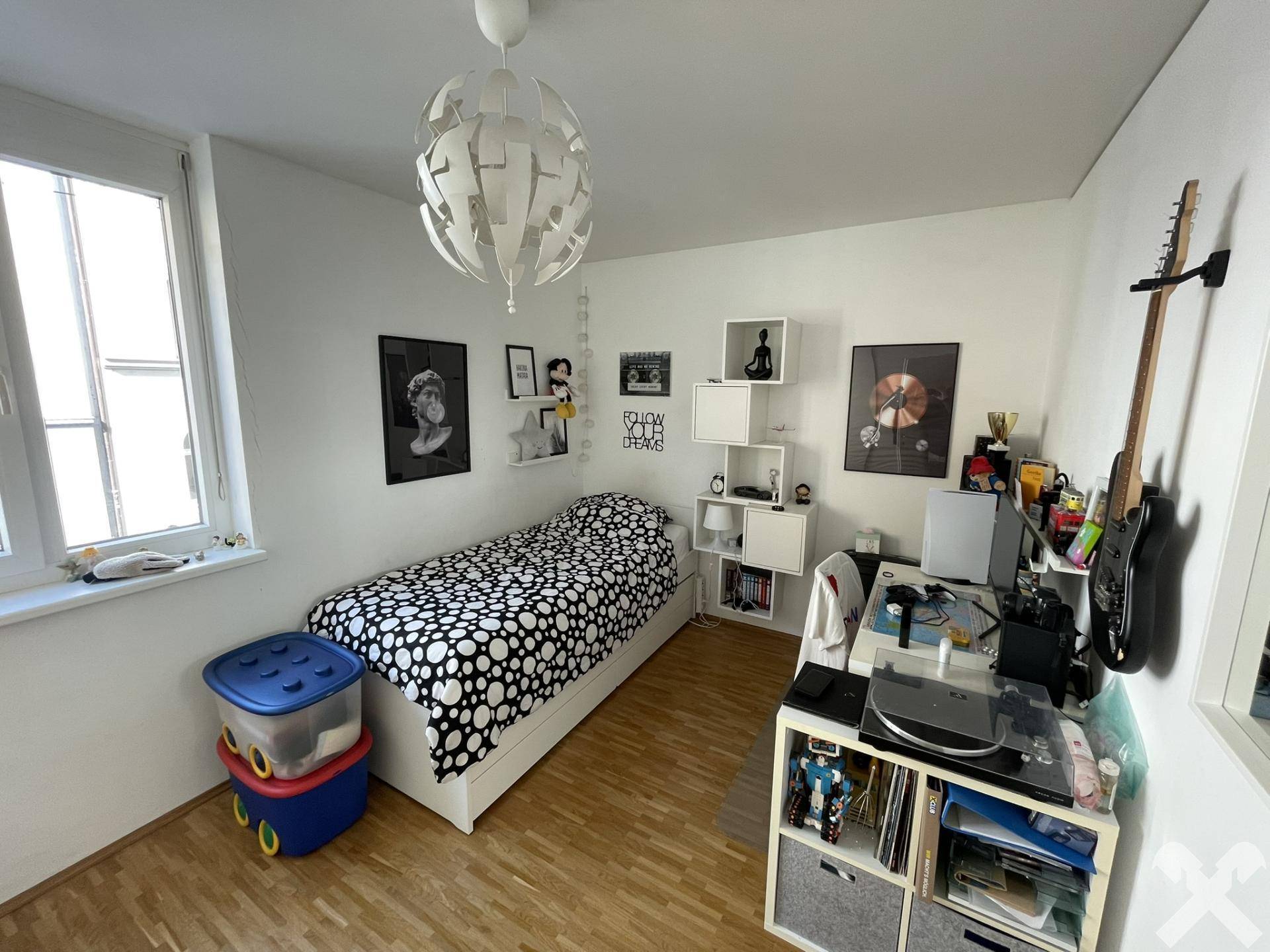 Helles Schlafzimmer mit Einzelbett, Holzboden und Fenster, eingerichtet für ein Kind oder Gast.