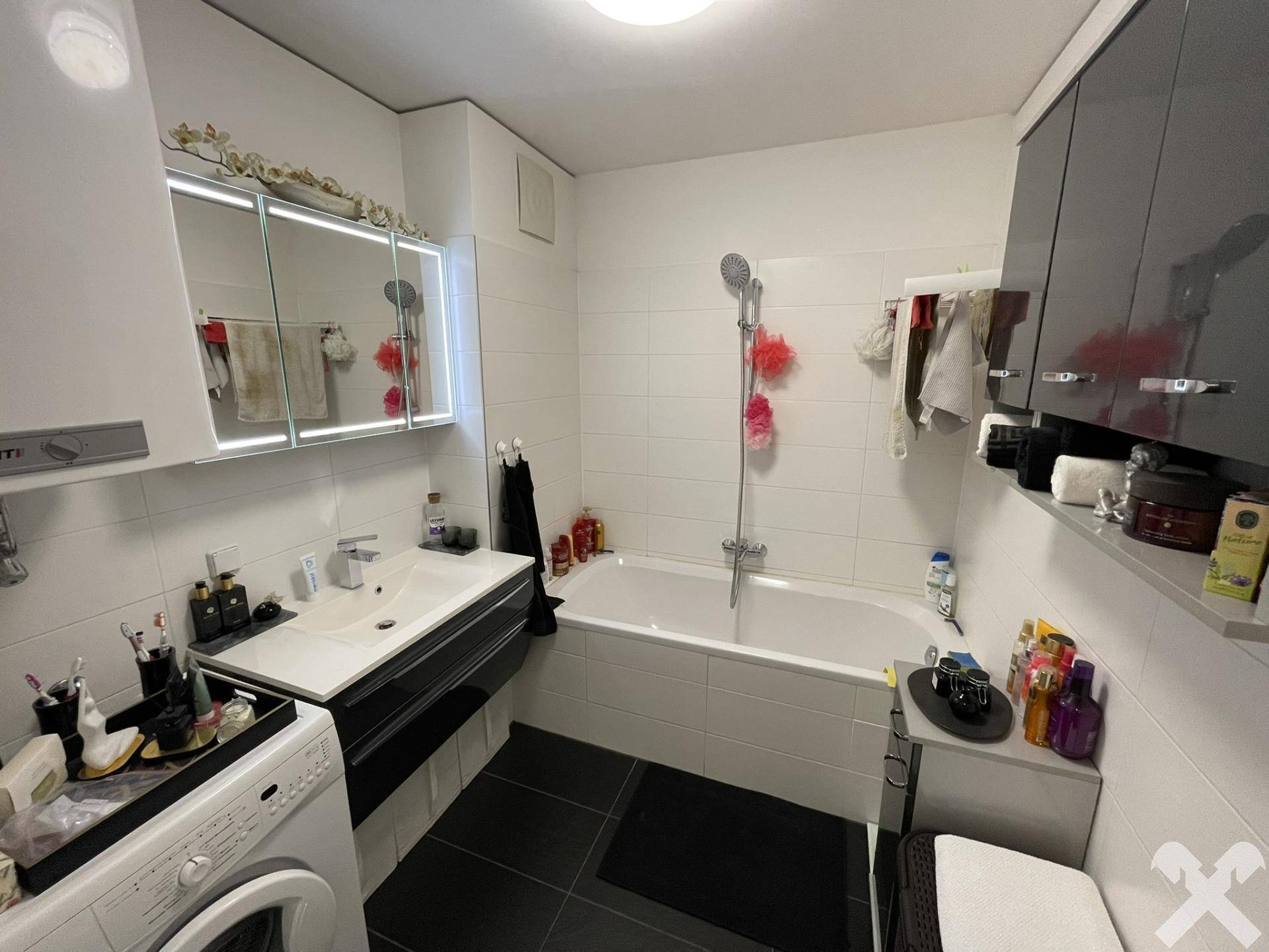 Modernes Badezimmer mit Badewanne, Waschbecken und dunklen Bodenfliesen.