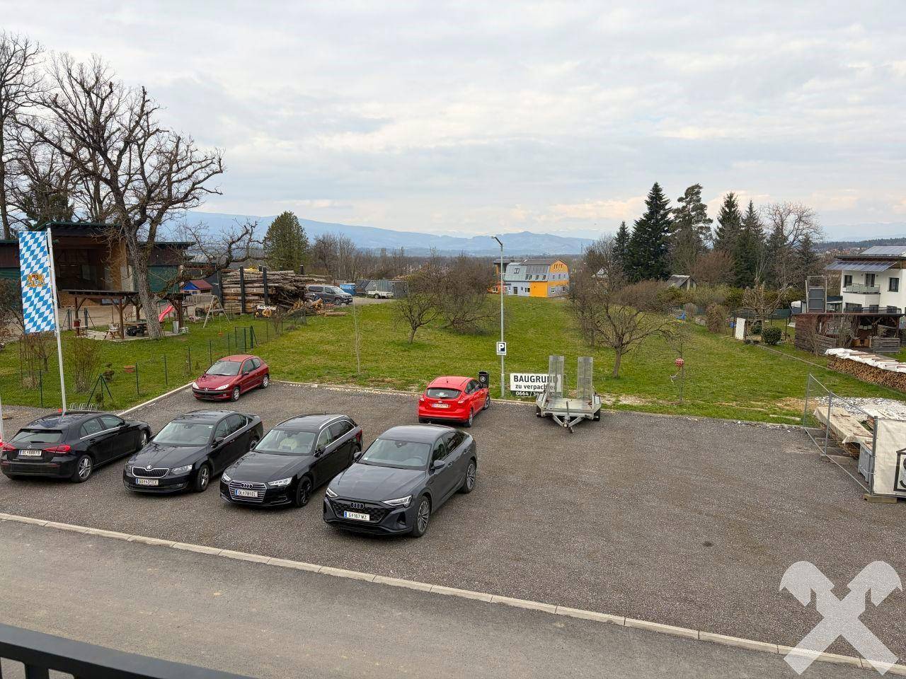 Außenbereich mit Parkplätzen und weitem Blick auf die umliegende grüne Landschaft und Berge.