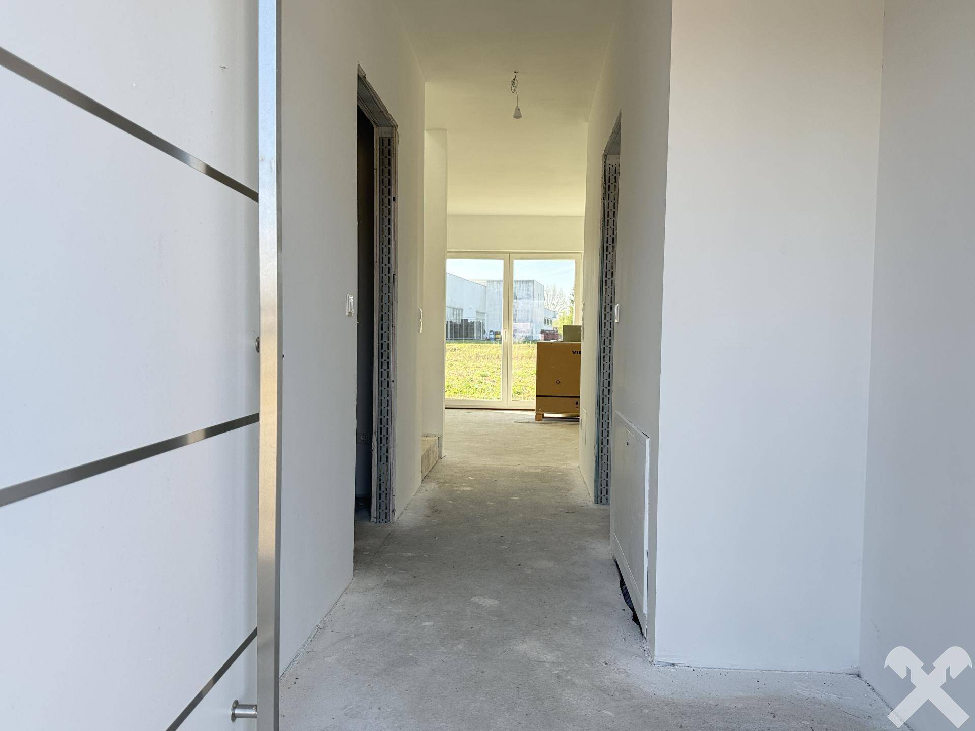 Eingangsbereich eines Neubaus mit Blick auf den Garten durch eine Terrassentür.