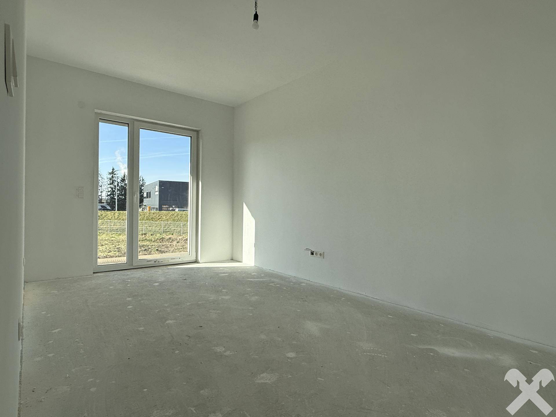Helles Zimmer mit großem Fenster und viel Tageslicht im Neubau.