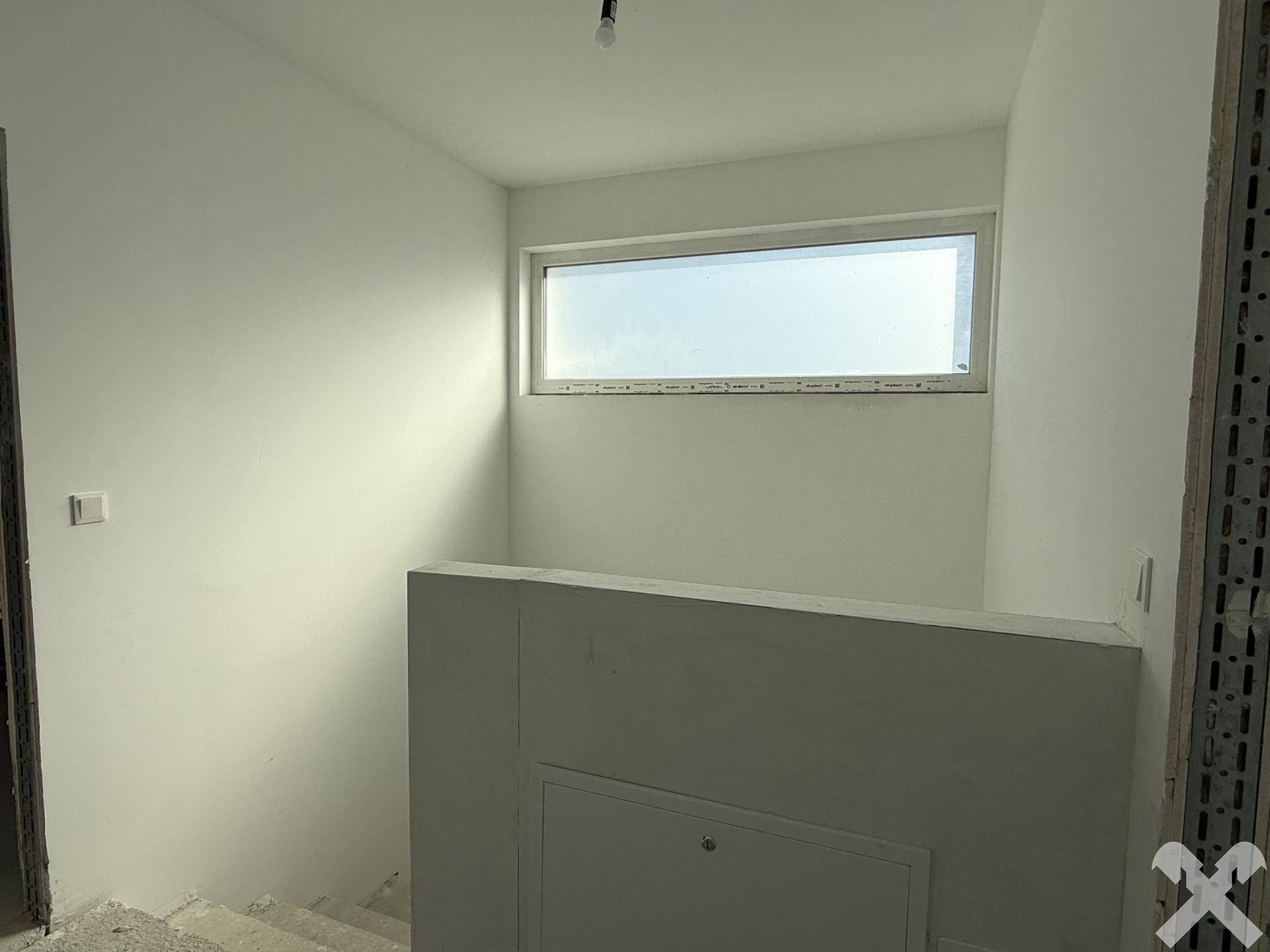Heller Treppenabsatz mit hohem Fenster, das viel Licht hereinlässt.