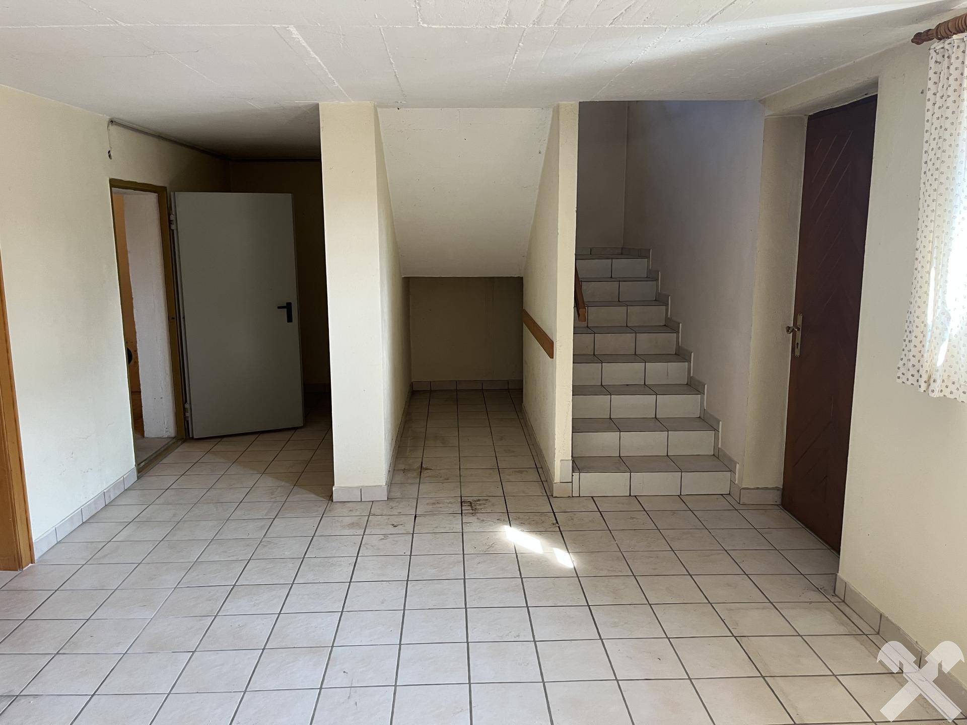 Kellerbereich mit Fliesenboden und Treppe zum Obergeschoss.