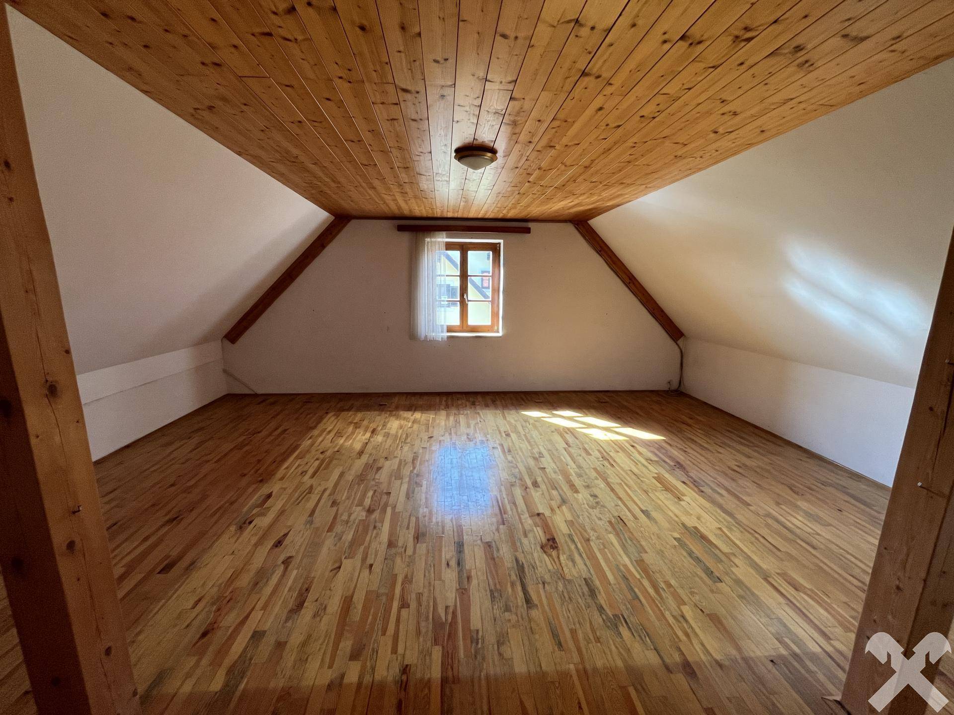 Großes Dachzimmer mit Holzdecke und Parkettboden, ideal als Schlaf- oder Hobbyraum.