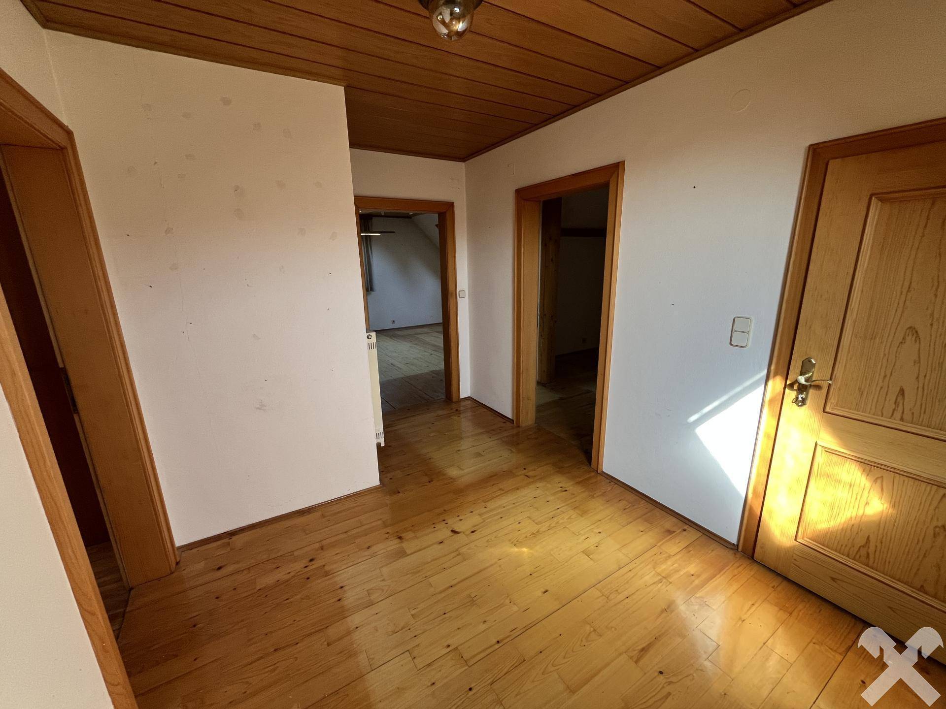 Flur im Obergeschoss mit Holzdeckenverkleidung und Parkettboden.