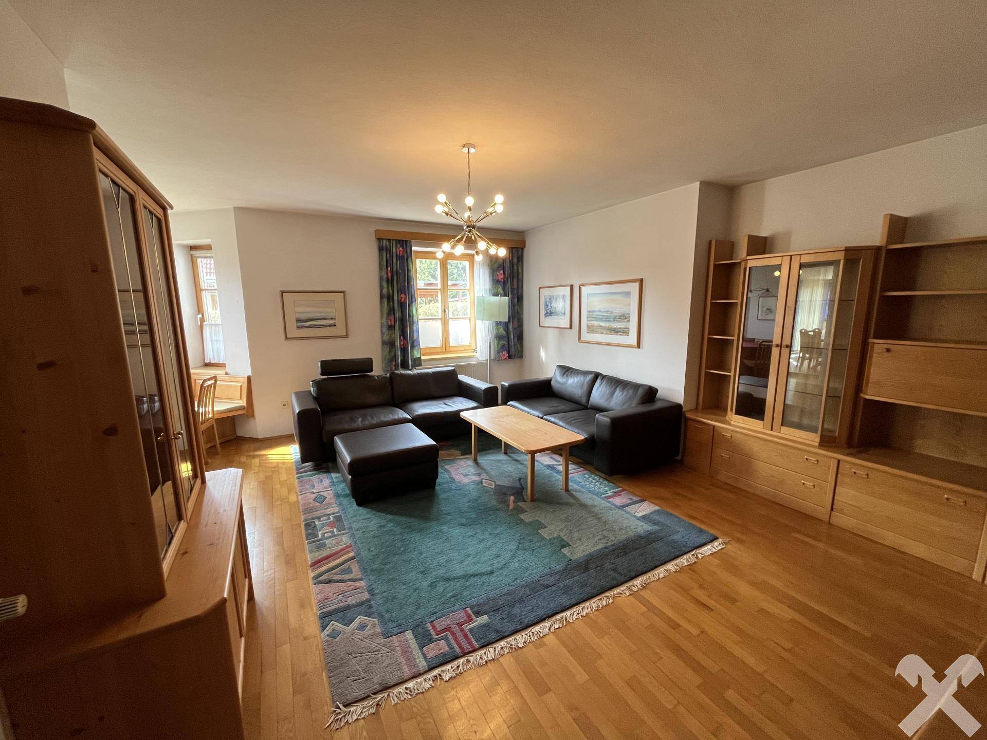 Geräumiges Wohnzimmer mit Parkettboden, großer Ledercouch und Holzmöbeln.