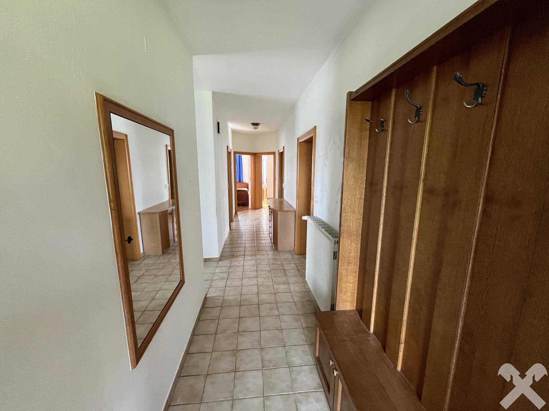 Heller Flur mit Fliesenboden, Garderobe und Spiegel.