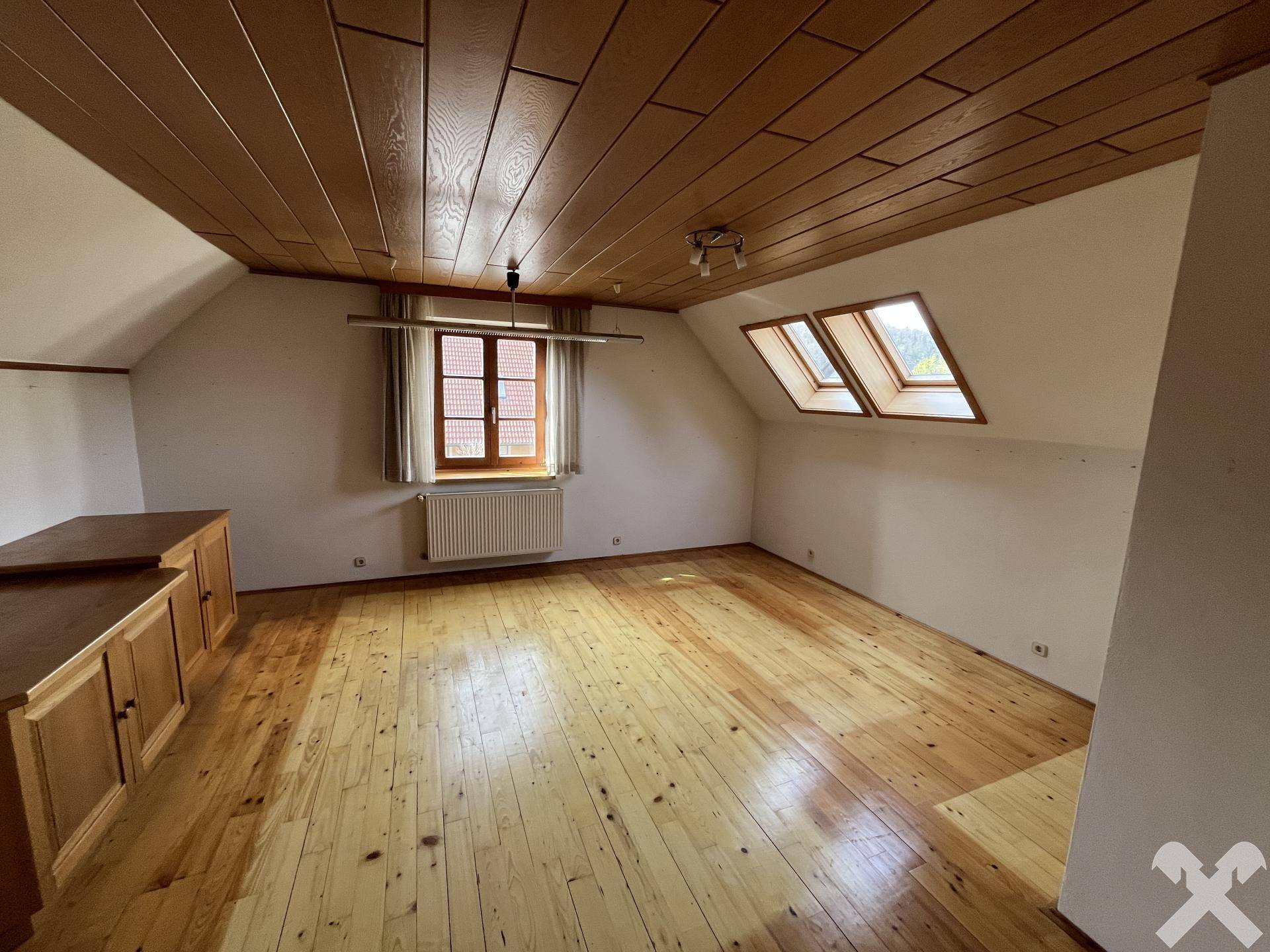 Geräumiges Dachzimmer mit Holzdecke, Parkettboden und Dachfenstern.