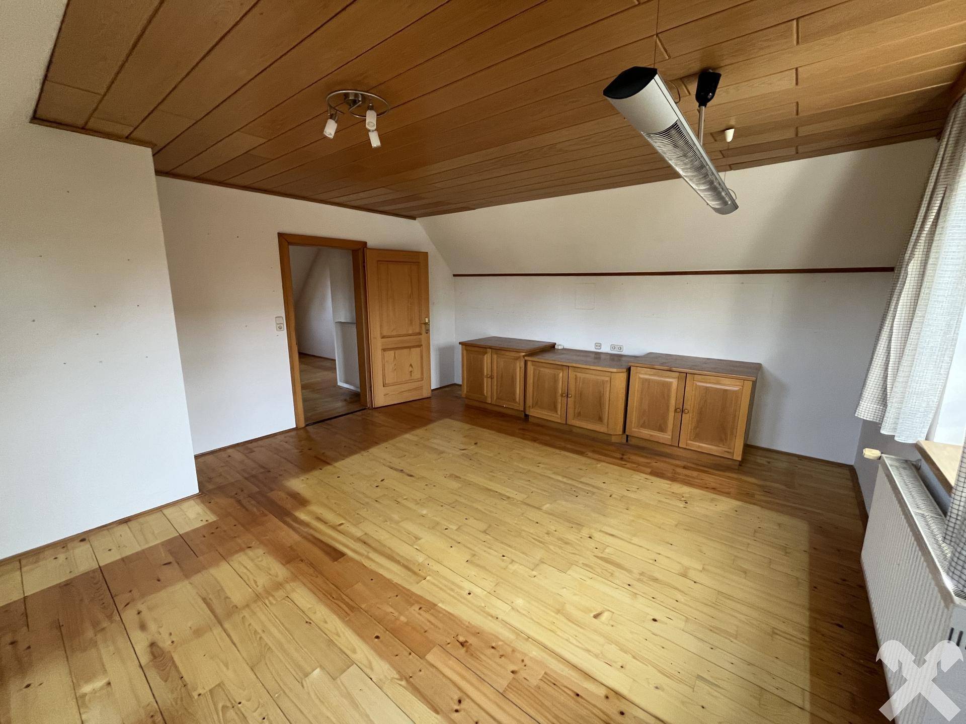 Helles Dachzimmer mit Holzdecke, Parkettboden und Einbauschränken.