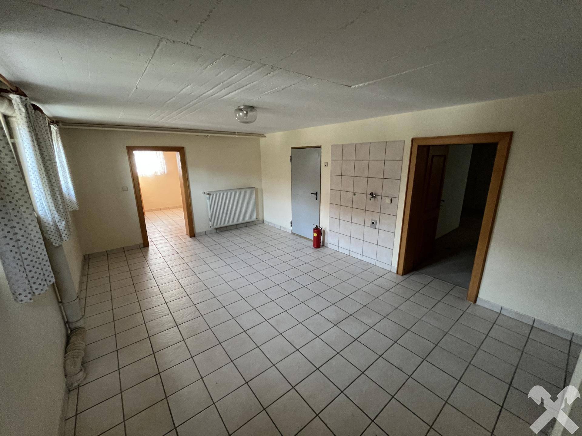 Geräumiger Kellerraum mit Fliesenboden und Zugang zu weiteren Räumen.