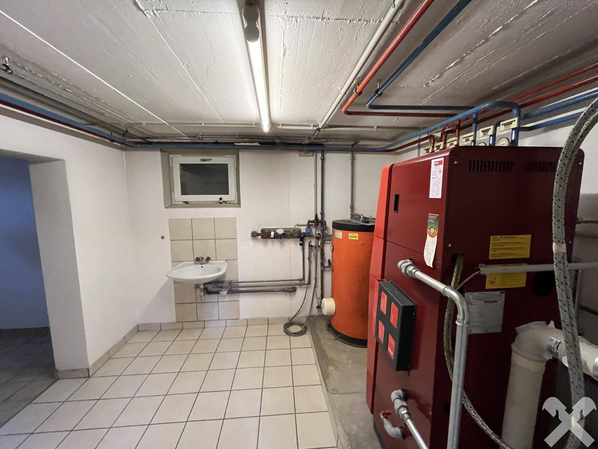 Heizungsraum im Keller mit technischen Anlagen und Waschbecken.