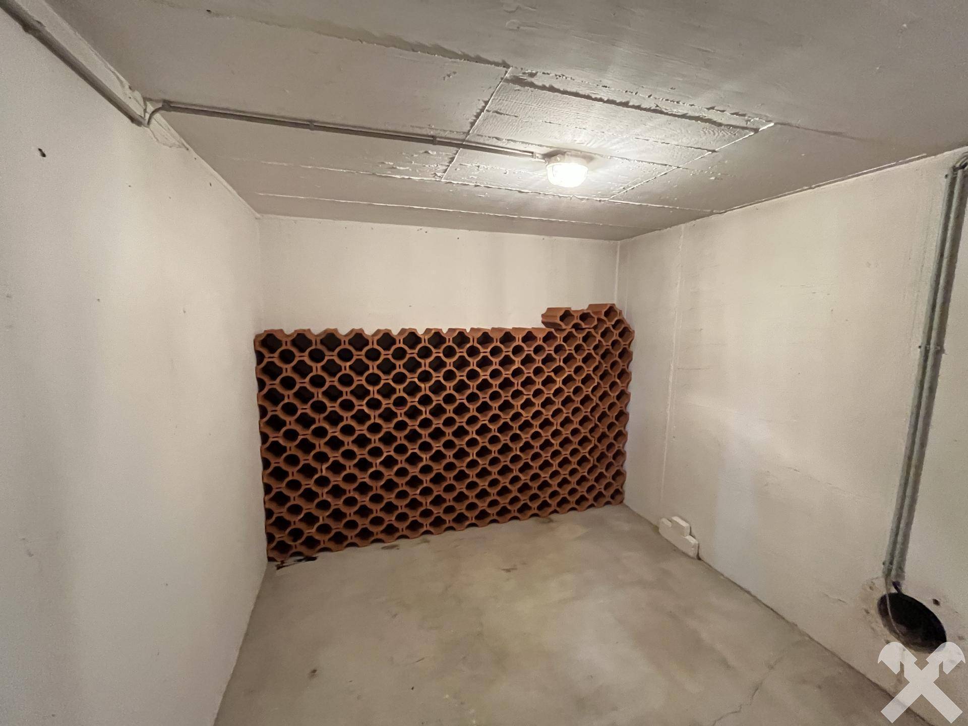 Kellerraum mit Weinregalen aus Terrakotta und Betonboden.