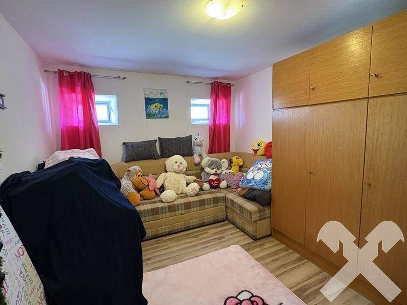 Gemütlicher Wohnraum mit Ecksofa, Laminatboden und Holzschränken.