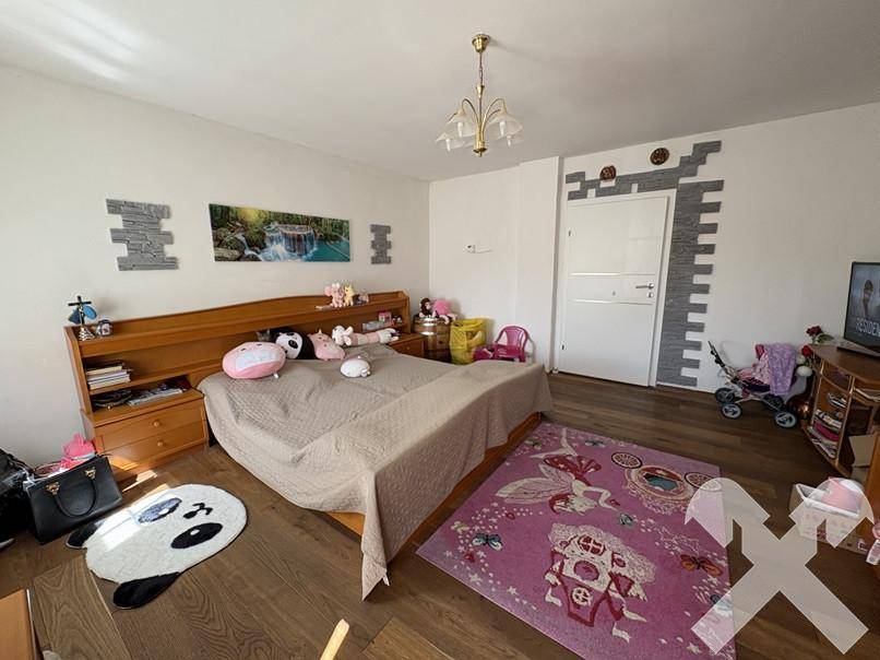Helles Schlafzimmer mit Holzboden, großem Bett und dekorativen Wandelementen.