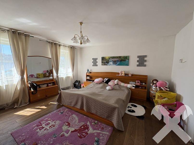 Geräumiges Schlafzimmer mit Holzbett, Parkettboden und großen Fenstern für viel Licht.