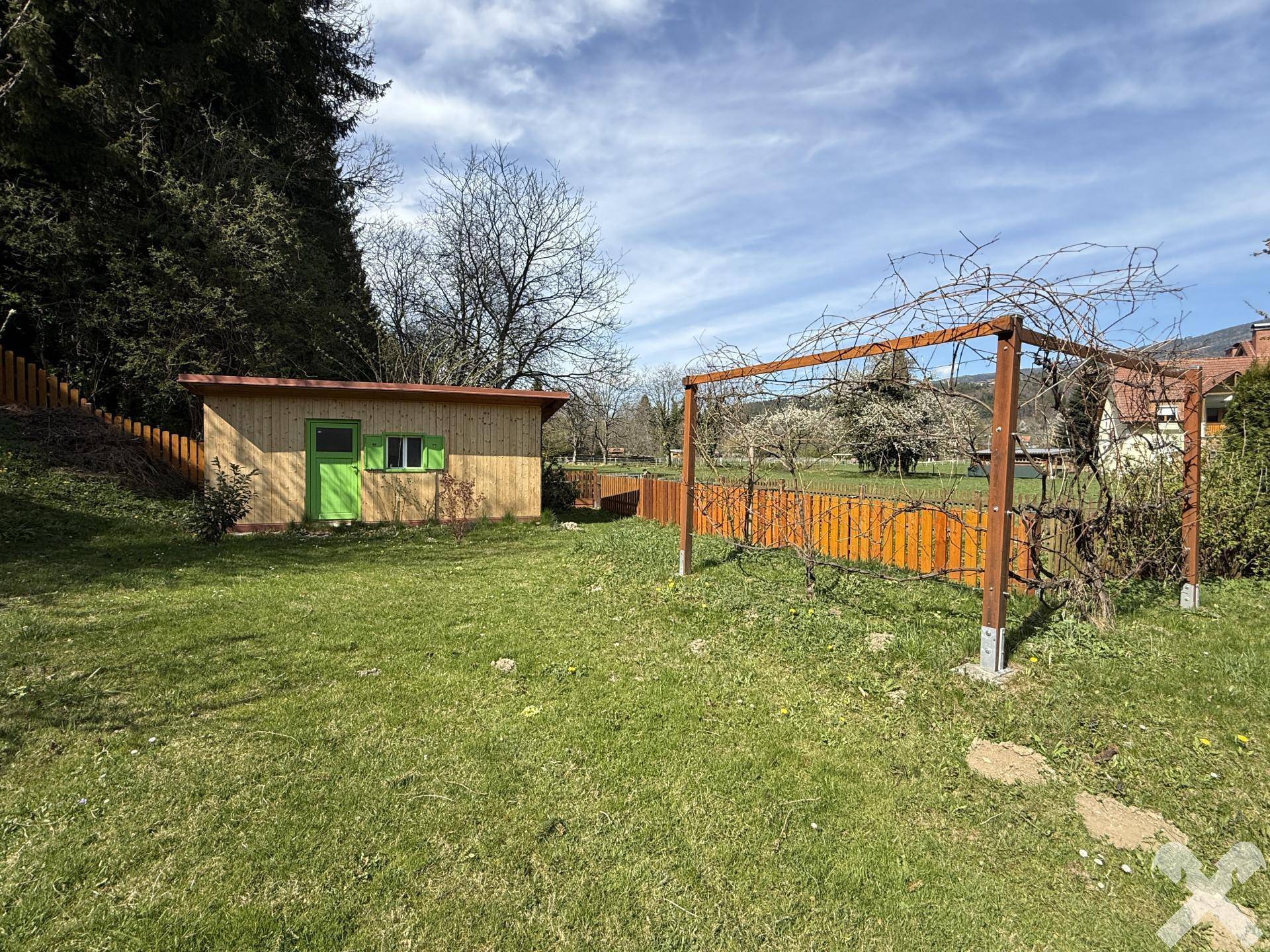 Grüner Garten mit Holzschuppen und Pergola, ideal für Entspannung im Freien.