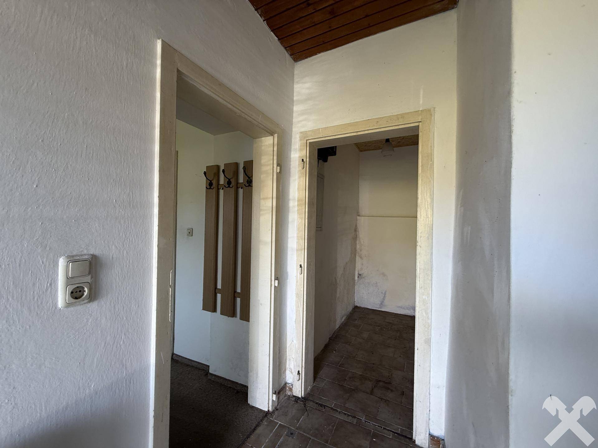 Flur mit Zugang zu einem Abstellraum und sichtbarer Holzbalkendecke.