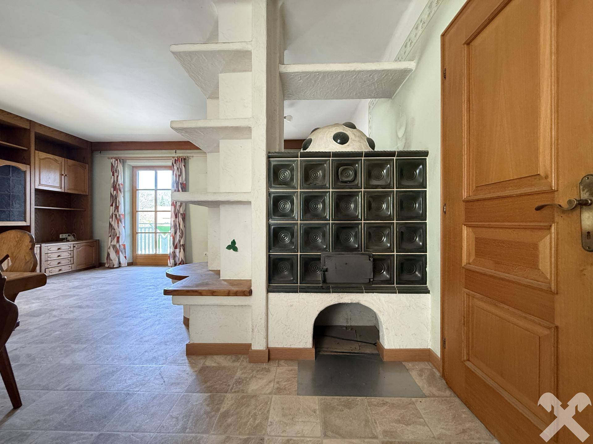 Detailansicht des traditionellen Kachelofens als Heizelement im Wohnbereich mit Holztür.