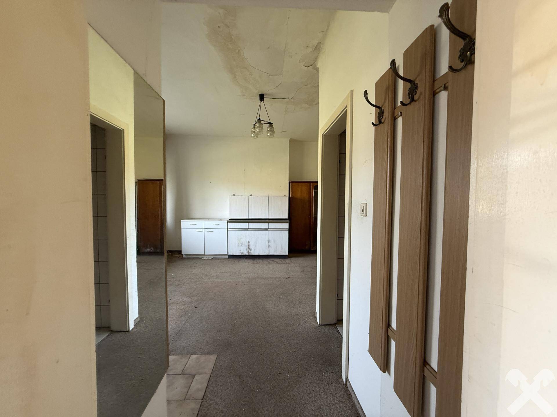 Flur mit Blick auf den Küchenbereich und Garderobe, bietet viel Potenzial.