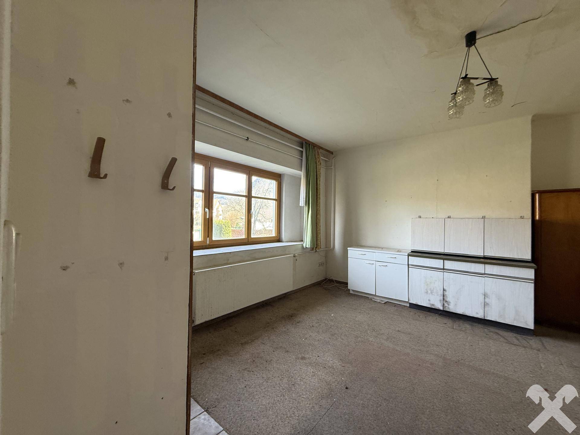 Leerer Raum mit einfacher Küchenzeile und Fenster, bereit für eine individuelle Gestaltung.