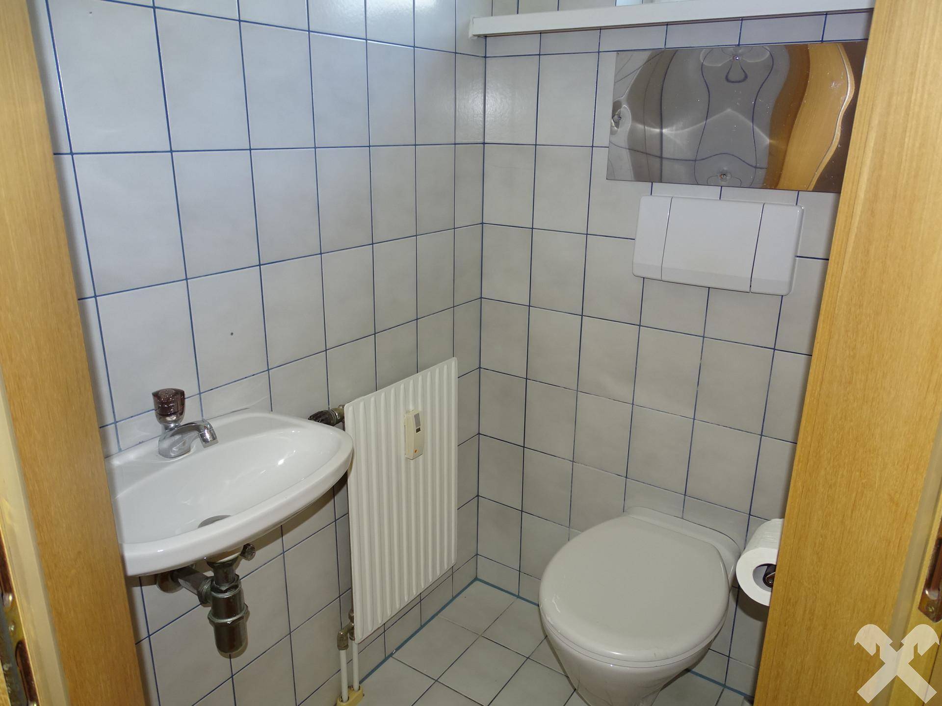 Kleines Gäste-WC mit Toilette, Waschbecken und hellblauen Fliesen.