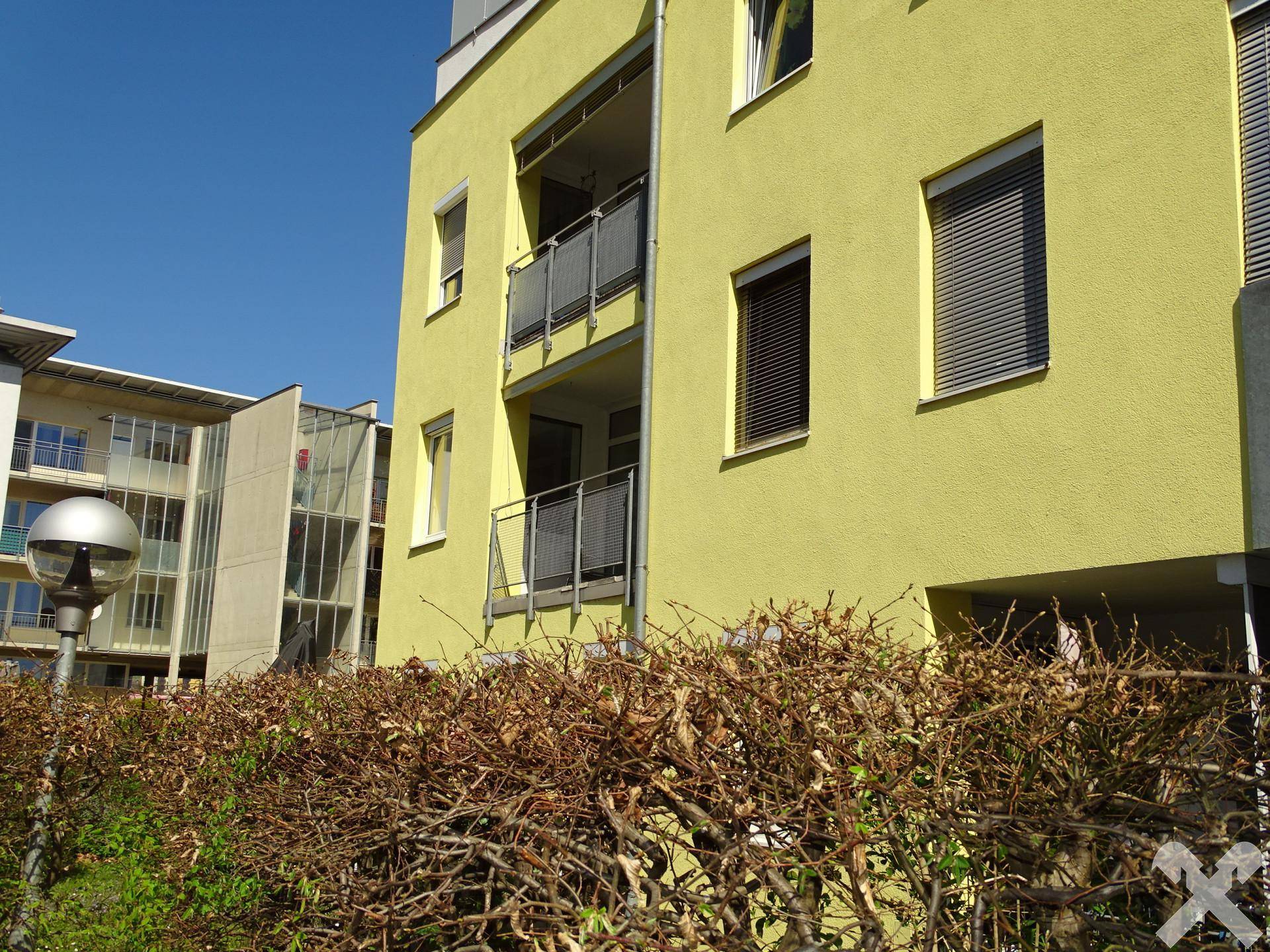 Seitenansicht der modernen Wohnanlage mit gelber Fassade und Balkonen.