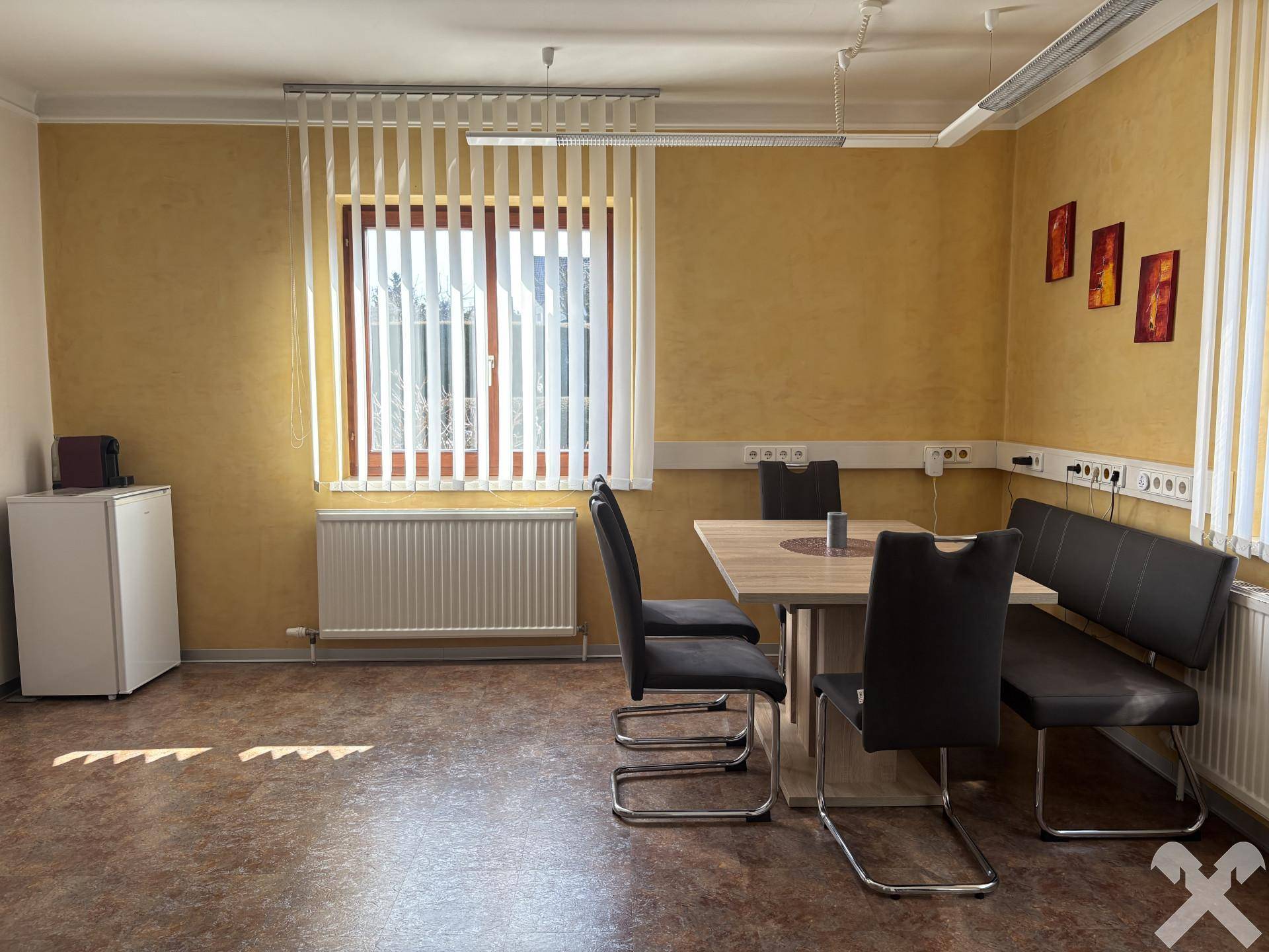Essbereich mit Holztisch, Sitzbank und Stühlen, umgeben von gelben Wänden und Fenstern.