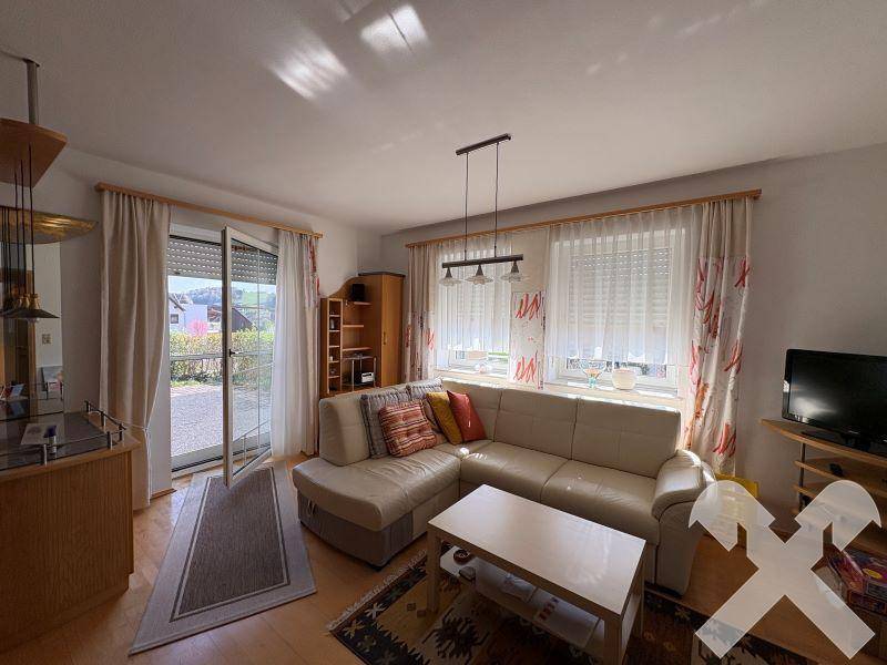 Heller Wohnbereich mit beigem Sofa, Holzboden und Zugang zur Terrasse.