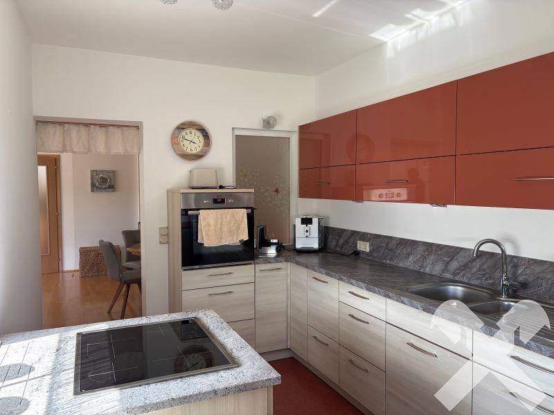 Moderne Küche mit glänzenden roten Oberschränken und Granit-Arbeitsplatten.