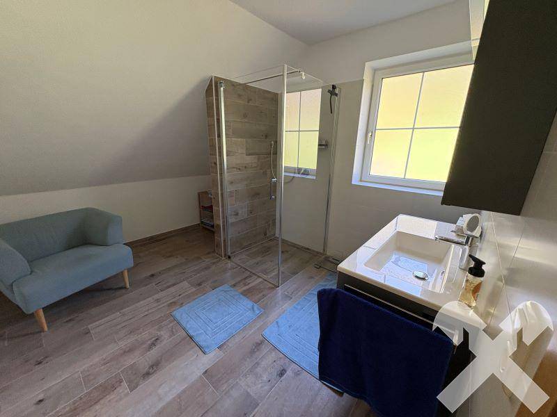 Modernes Badezimmer im Dachgeschoss mit begehbarer Dusche und großem Fenster.