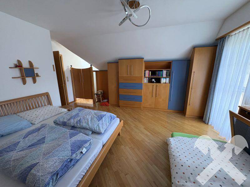 Geräumiges Schlafzimmer im Dachgeschoss mit Holzboden und Einbauschränken.