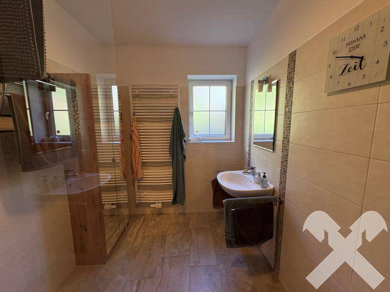 Helles Badezimmer mit Fliesenboden, Einzelwaschbecken und beheiztem Handtuchhalter.