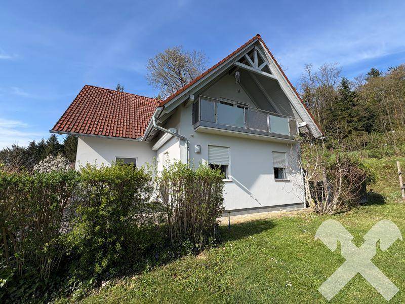 Rückansicht des Hauses mit Balkon im Obergeschoss und umgebender Natur.