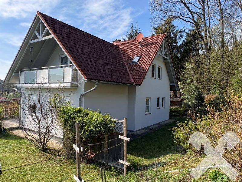 Seitenansicht des Hauses mit Balkon und Blick auf die umliegende Natur.