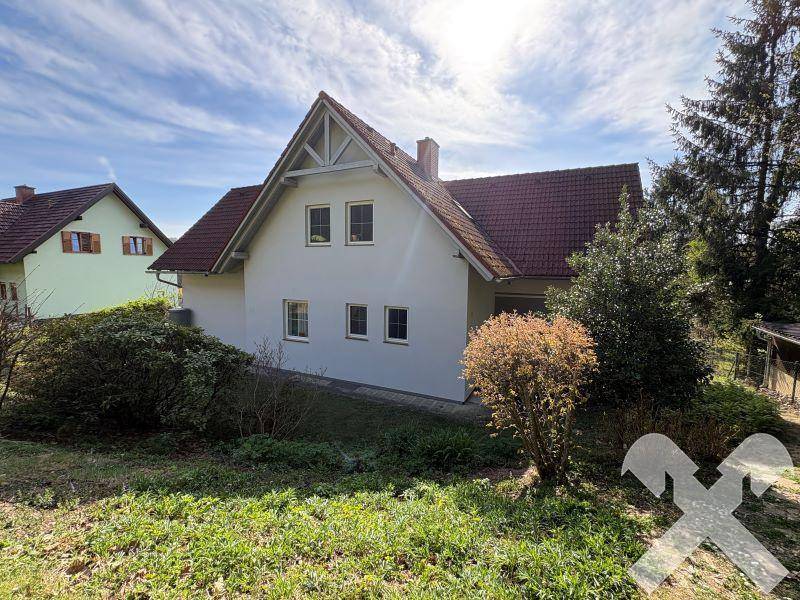 Rückansicht des Einfamilienhauses mit Garten und umgebender grüner Landschaft.