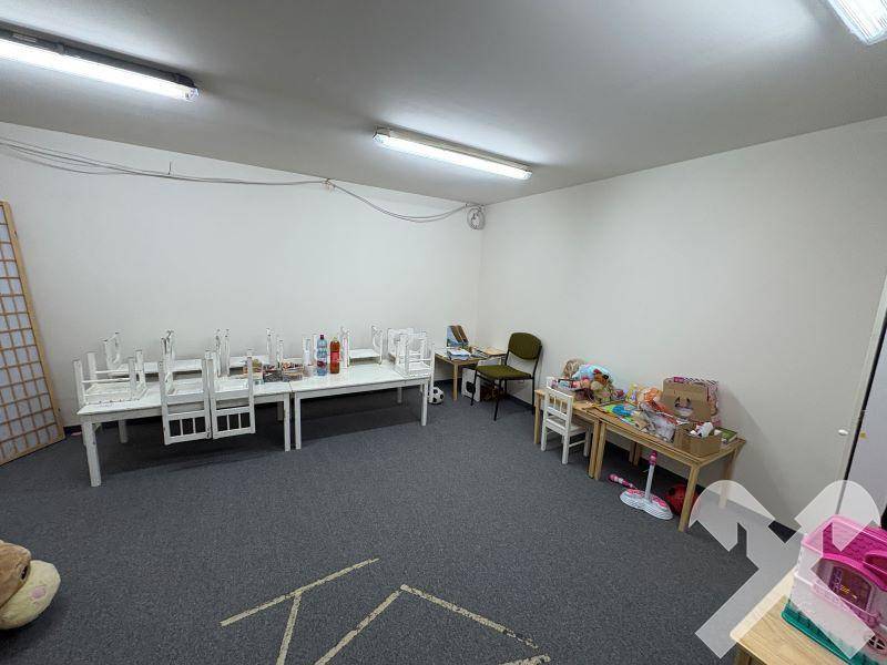 Großer Raum mit Teppichboden, Kindermöbeln und Spielzeug, ideal als Spielbereich.