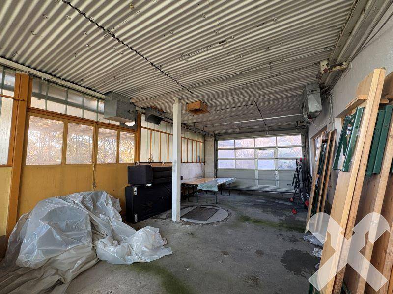 Geräumige Garage oder Werkstatt mit Rolltor, Betonboden und Lagerflächen.