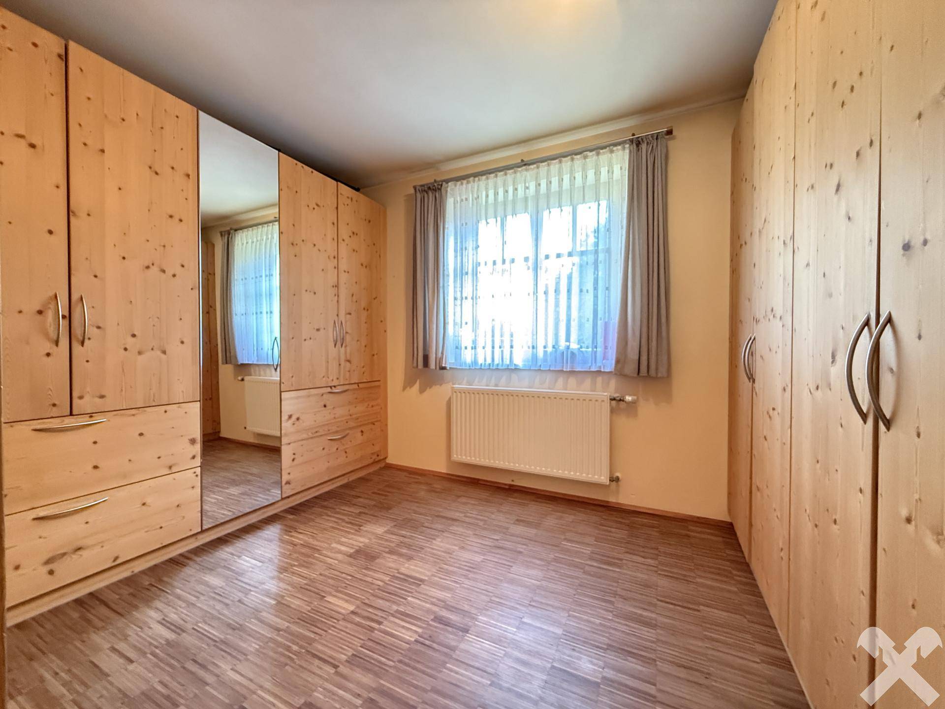 Helles Schlafzimmer mit Holzboden und großen Einbauschränken aus hellem Holz.