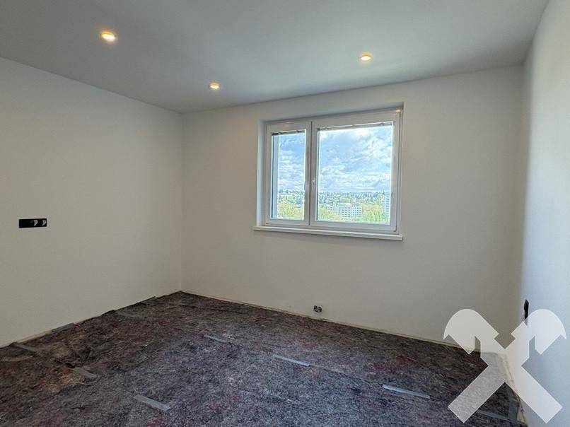 Helles Zimmer im Rohbau mit Bodenschutz und großem Fenster, ideal für Schlaf- oder Arbeitszimmer.