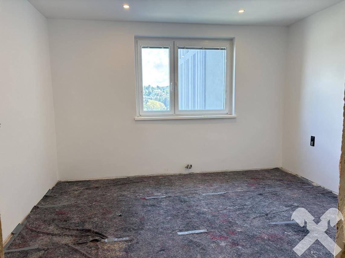 Zimmer im Rohbau mit Bodenschutz und großem Fenster, bereit für den finalen Ausbau.