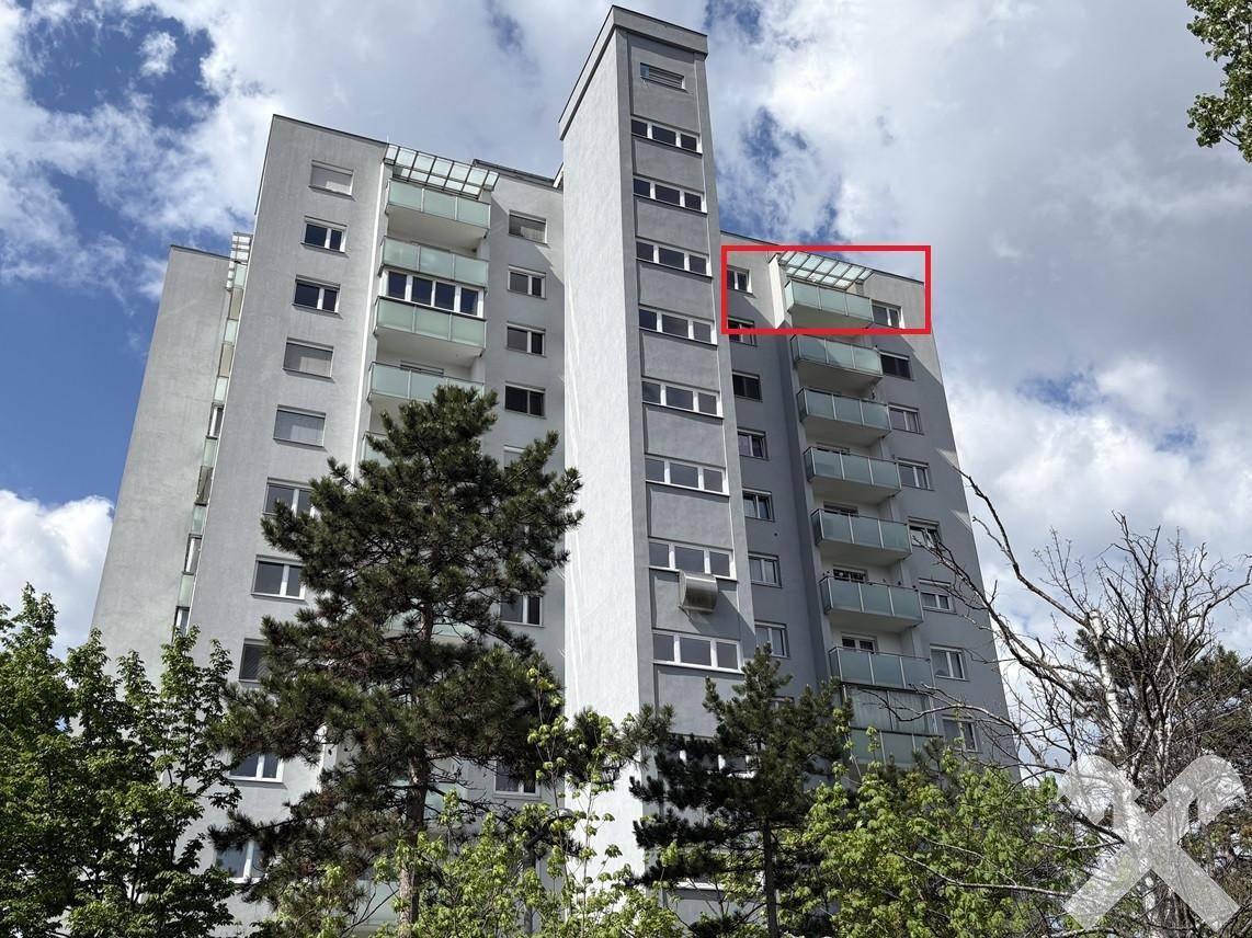 Hohes Wohngebäude mit vielen Balkonen und moderner Architektur unter blauem Himmel.