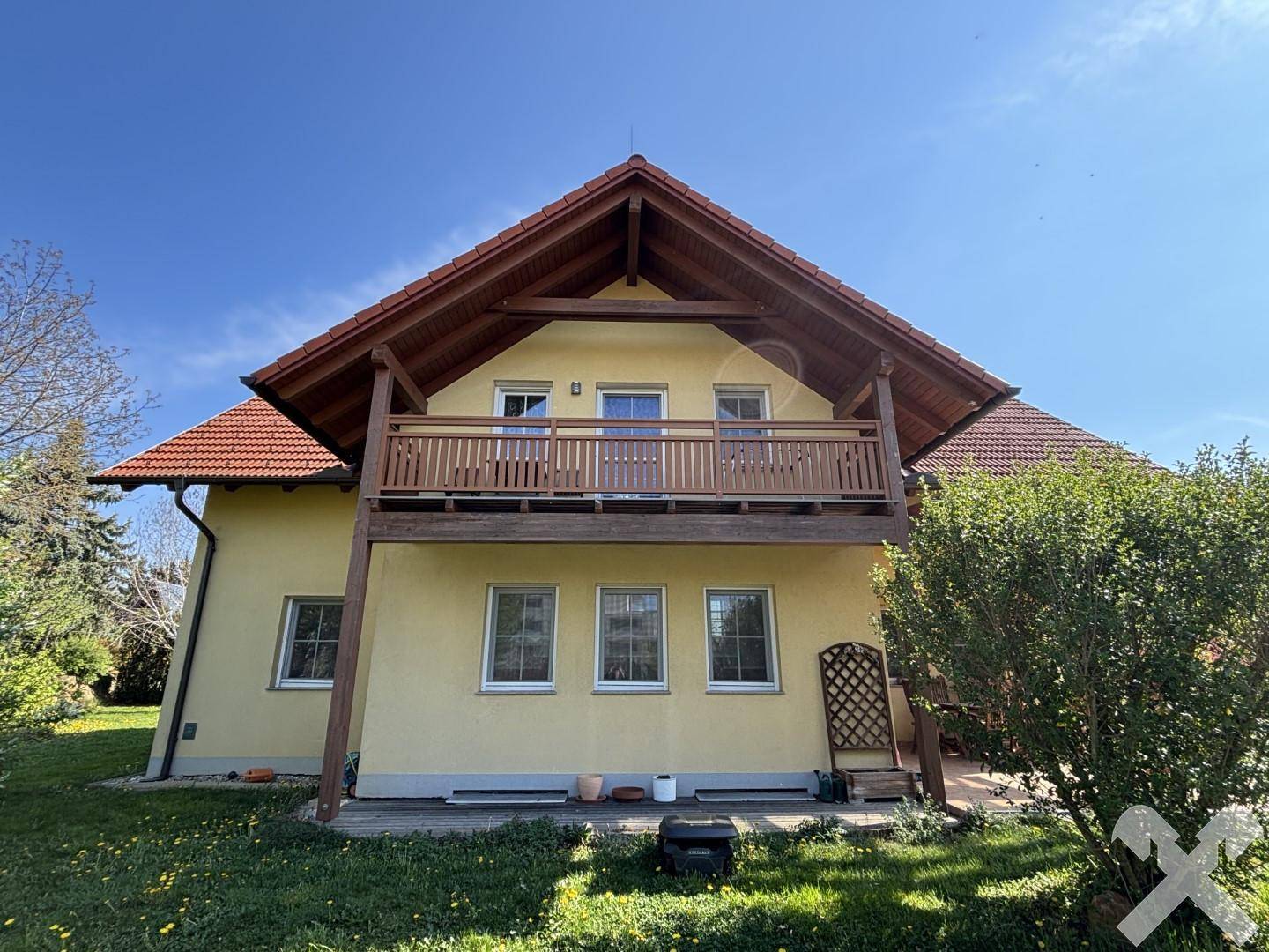 Rückseite des Hauses mit einem großen Holzbalkon und Blick ins Grüne.