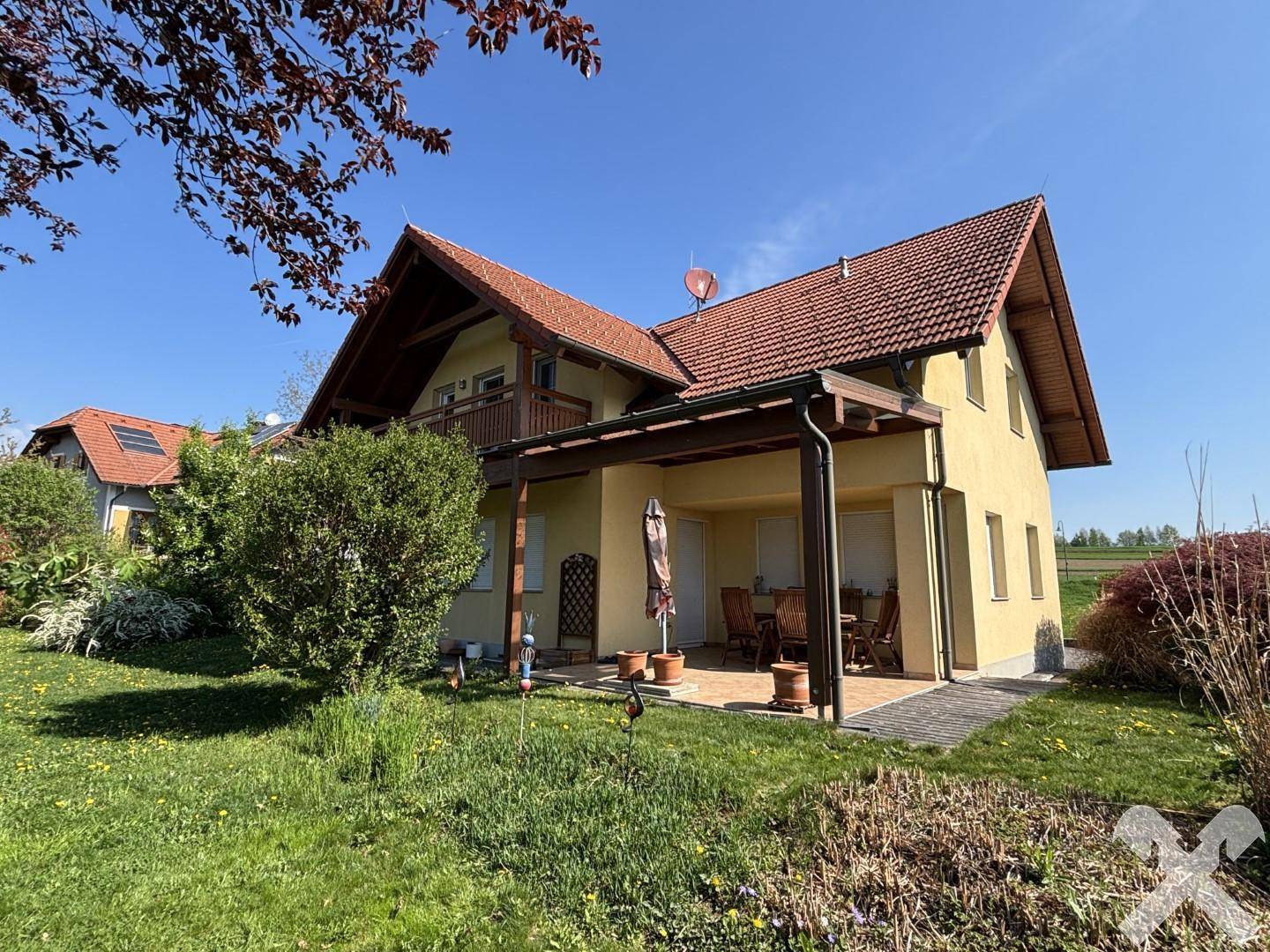Sonniger Außenbereich mit überdachter Terrasse und Gartenblick, ideal für Entspannung.