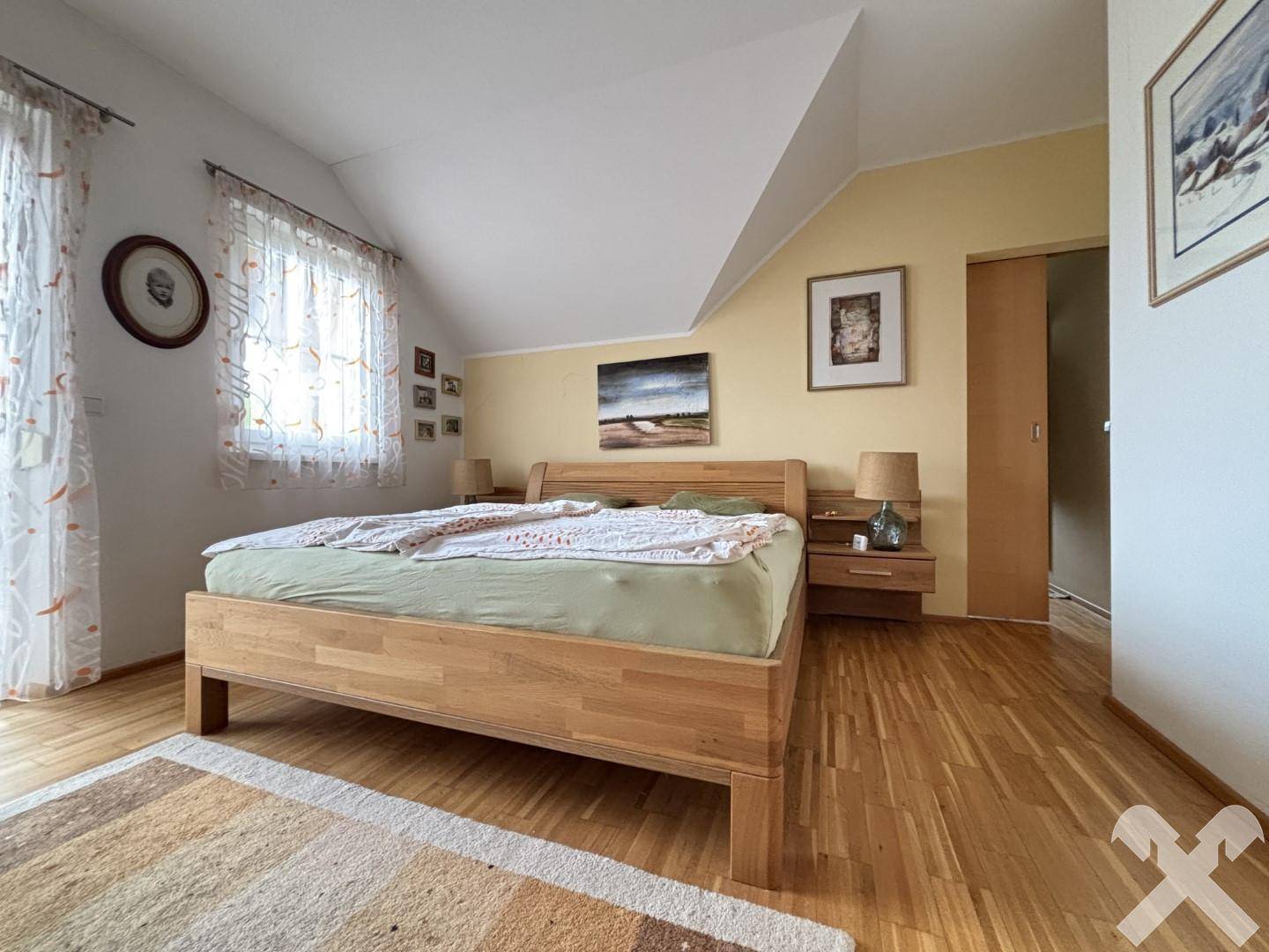 Gemütliches Schlafzimmer mit Holzbett, Parkettboden und Dachschräge.