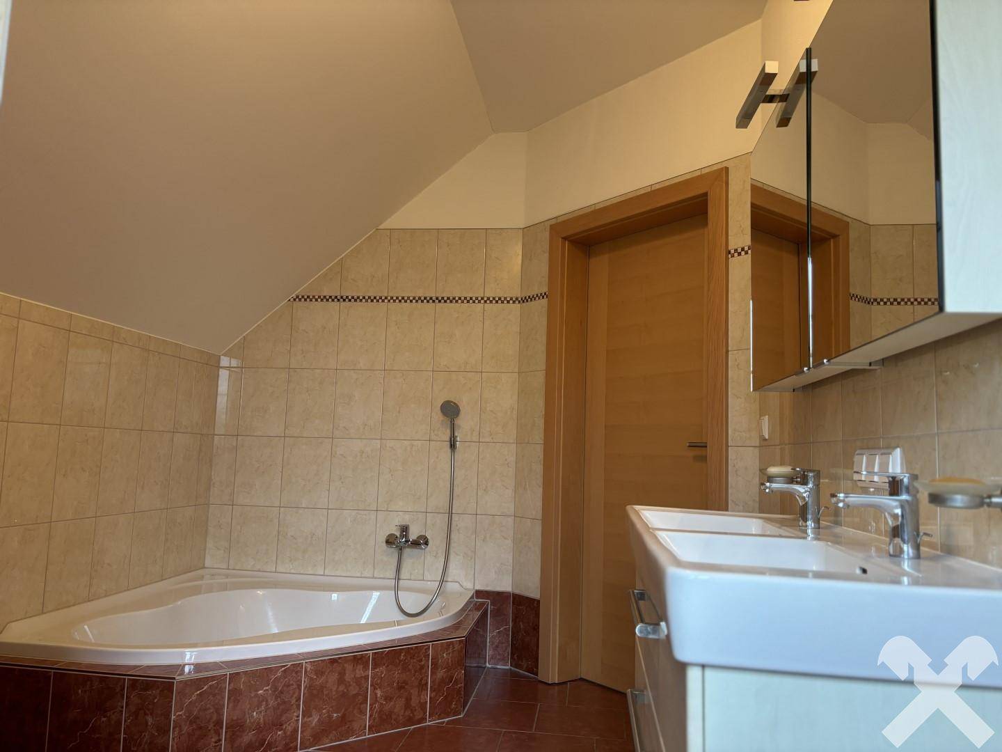 Geräumiges Badezimmer mit Eckbadewanne, Doppelwaschbecken und Dachschräge.