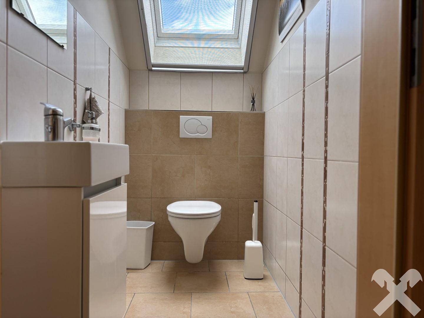 Modernes Gäste-WC mit wandhängendem WC, Waschbecken und Dachfenster.
