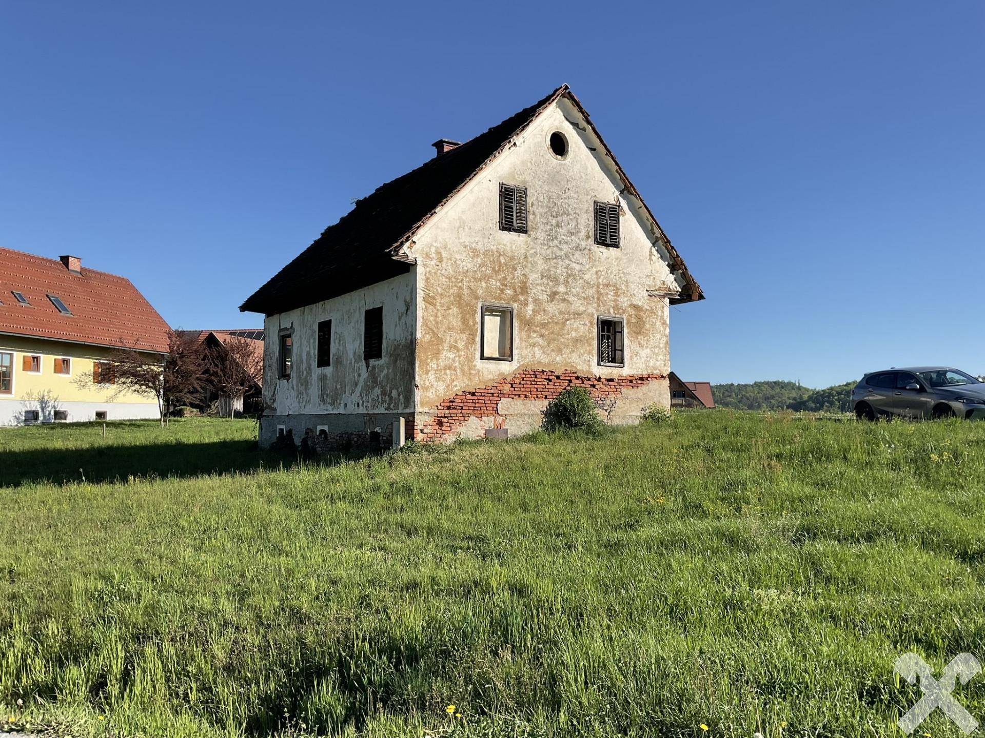Rückansicht des alten Hauses mit bröckelndem Putz und Blick auf die umliegende Landschaft.