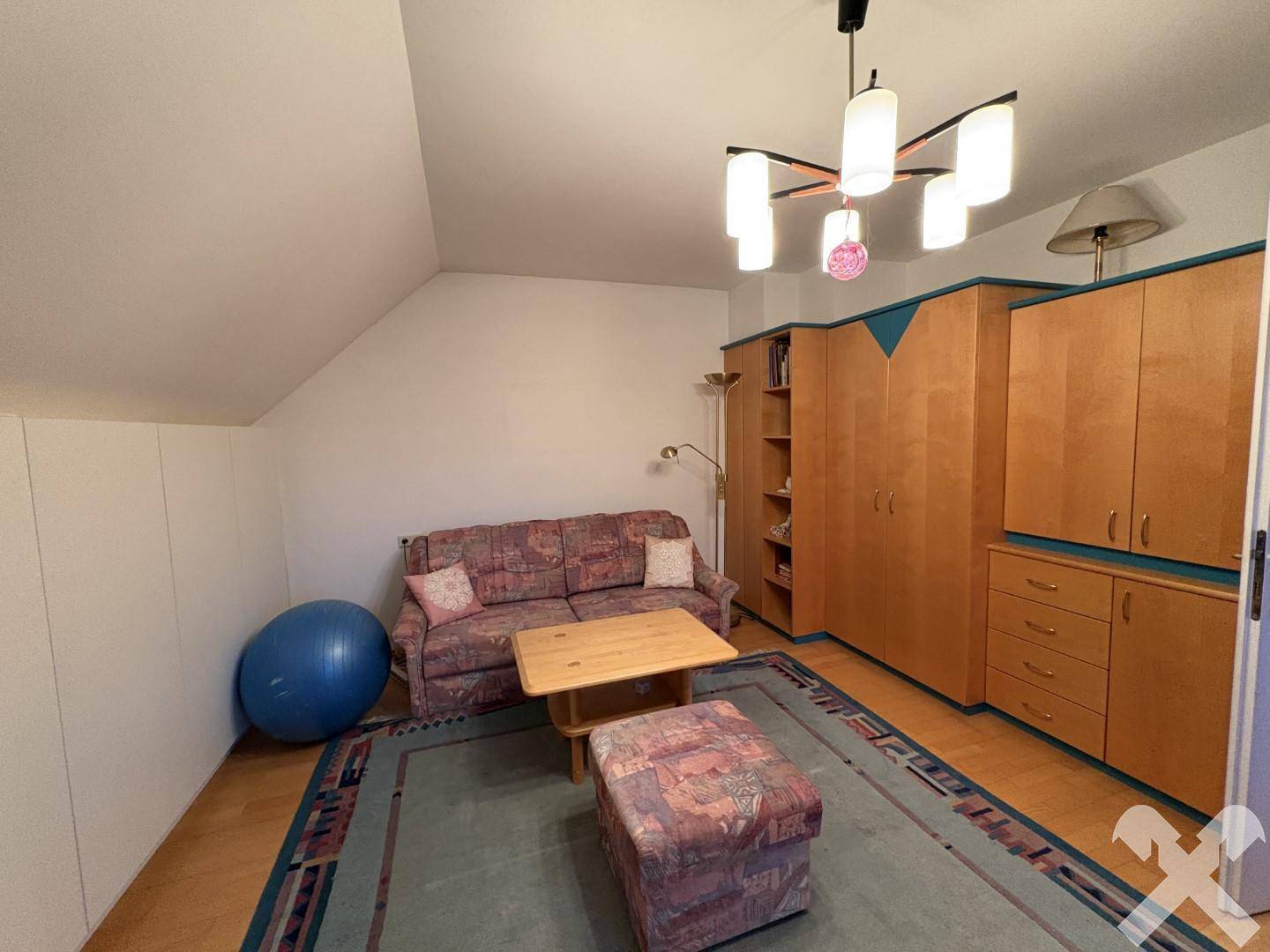 Gemütlicher Wohnbereich im Dachgeschoss mit Schrägen, Sofa und Holzmöbeln für entspannte Stunden.
